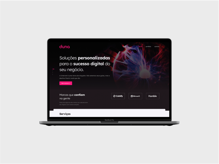 A primeira seção da home page do site da Duna Criativa, aberto em um MacBook Pro, de frente para à tela, num fundo branco acizentado.