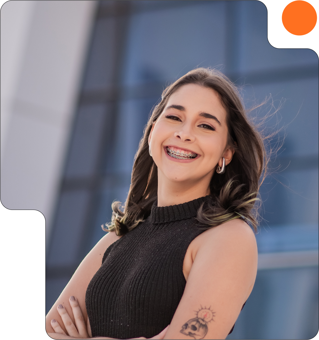 Lethicia sorrindo enquanto olha para a câmera com os braços cruzados